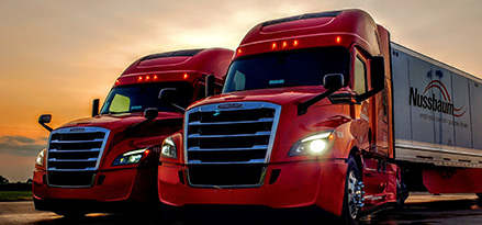 Two red fleet trucks with lights on