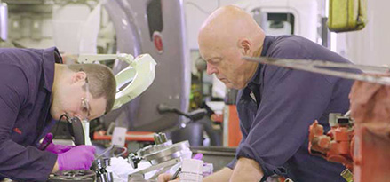 Two technicians working on truck engine together